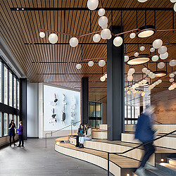 A group of people walking around a building with a large chandelier.